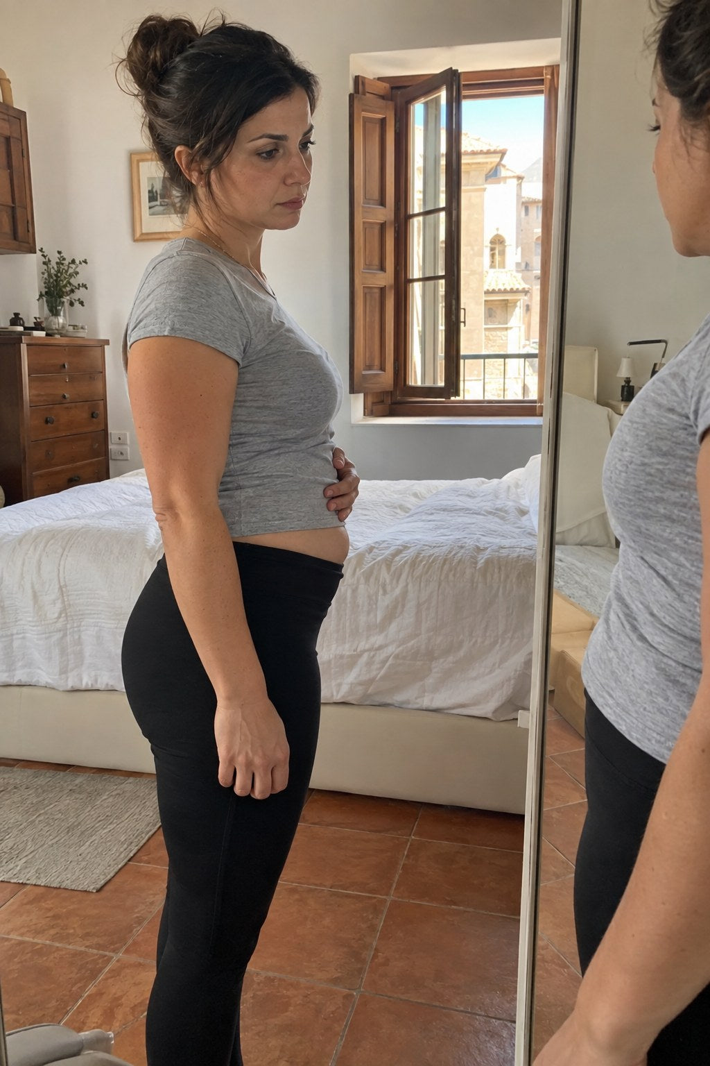 Mamma di profilo davanti allo specchio che si guarda la pancia